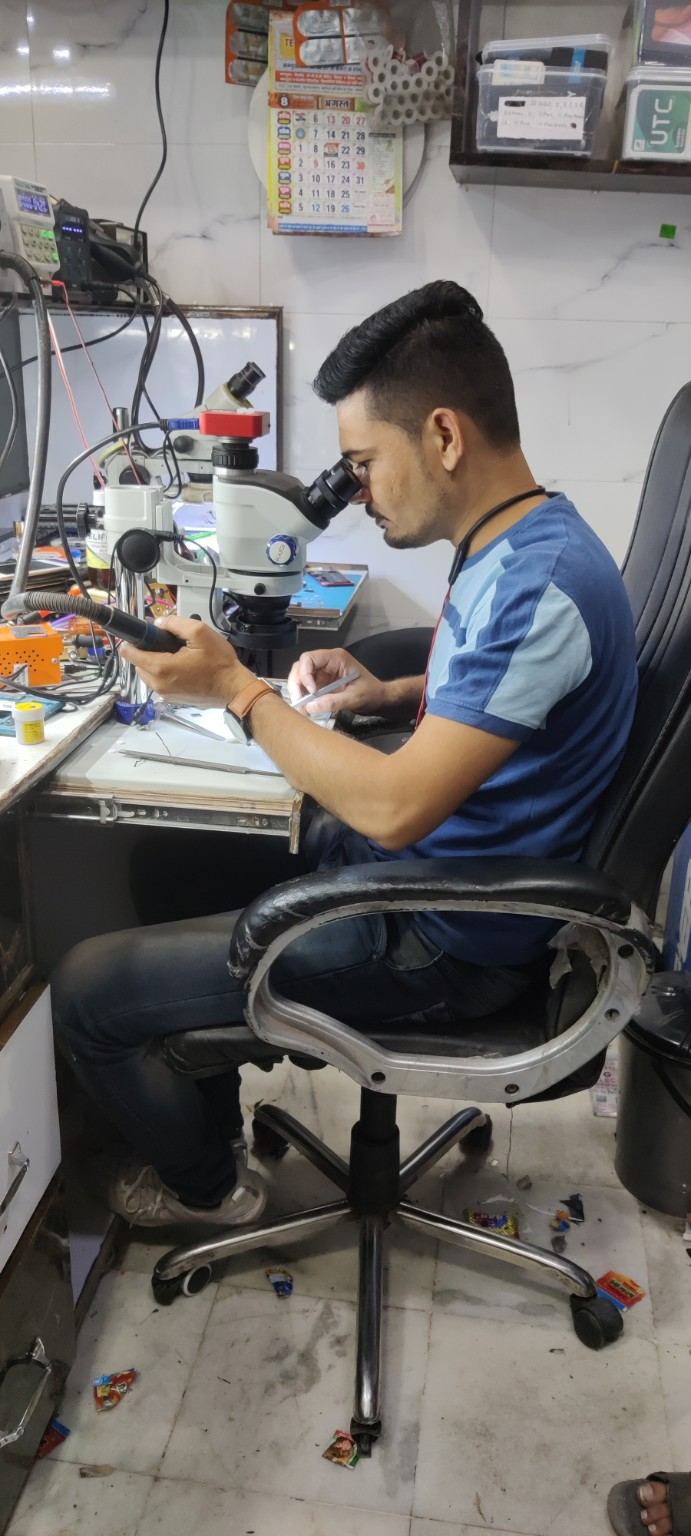BELIM technician performing precision motherboard repair under microscope